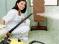 Young woman steam cleaning the bathroom